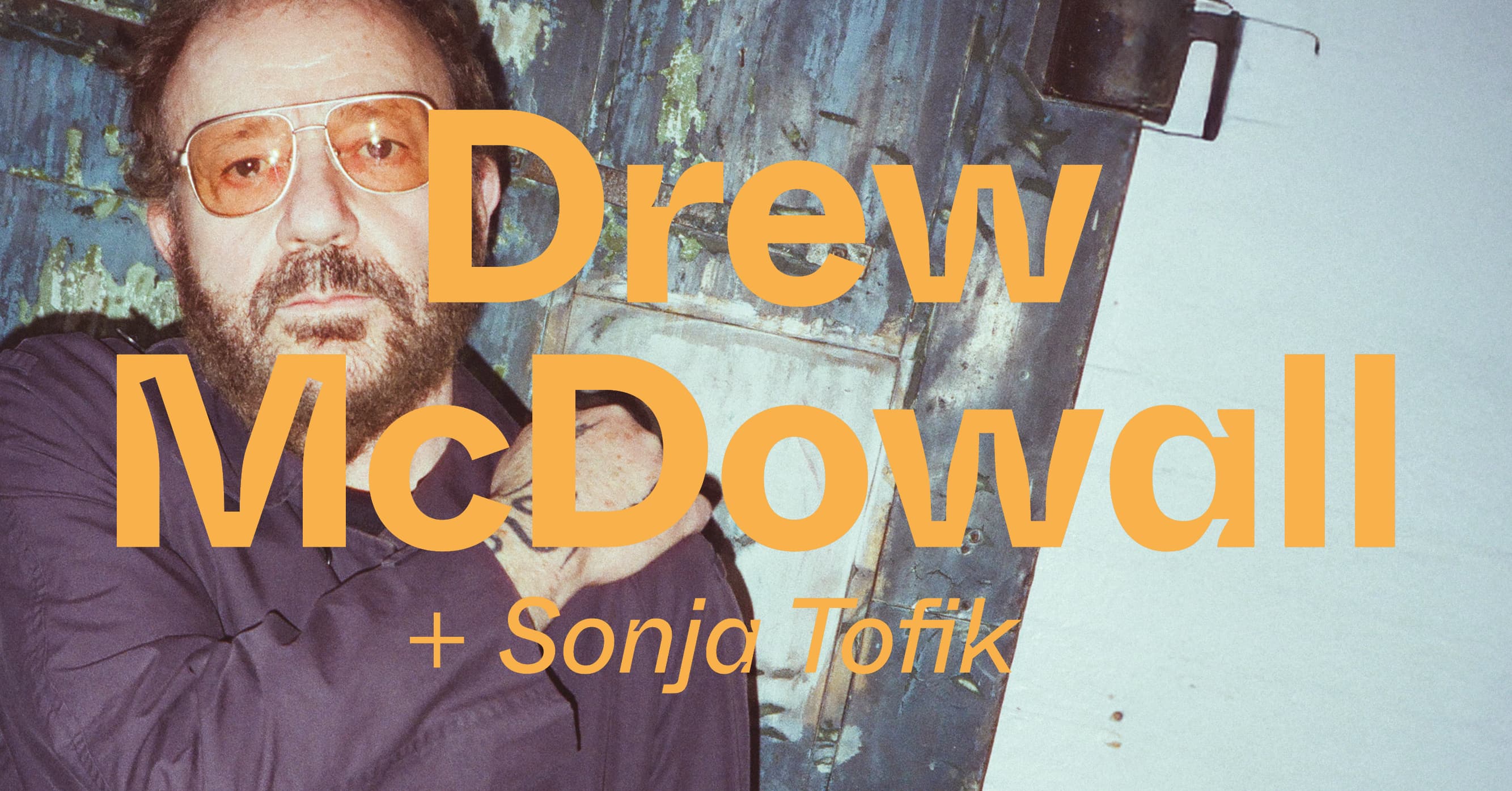 A bearded man wearing sunglasses is partially visible, with the text "Drew McDowall + Sonja Tofik" in large orange letters across the image.