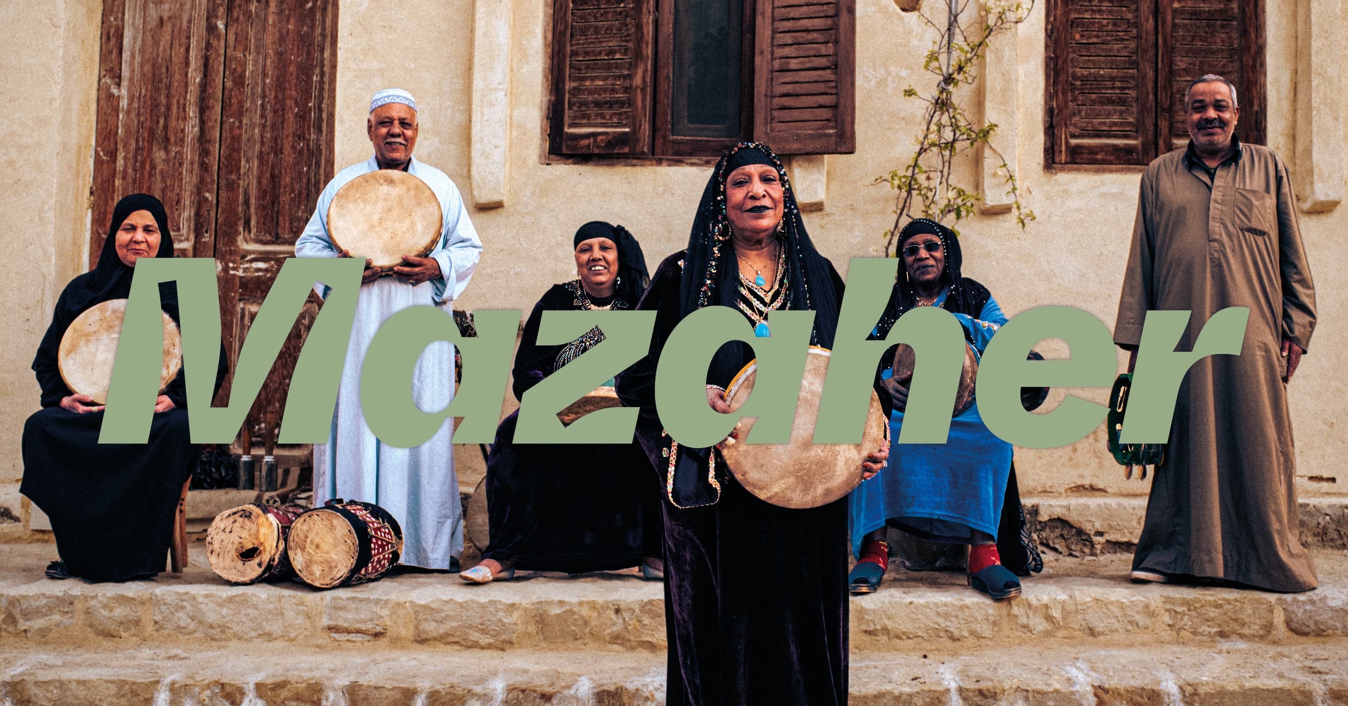 A group of six people in traditional attire hold percussion instruments, with the word "Mazaher" overlaid in large green text.